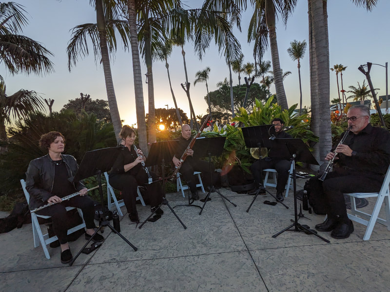 Wind quintet performing at the Bali Hai for wedding music while sun sets in background.